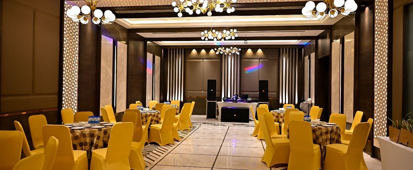 Event space with round tables and chairs arranged, featuring fancy lights hanging from the ceiling at BluSalzz Residence, Amritsar